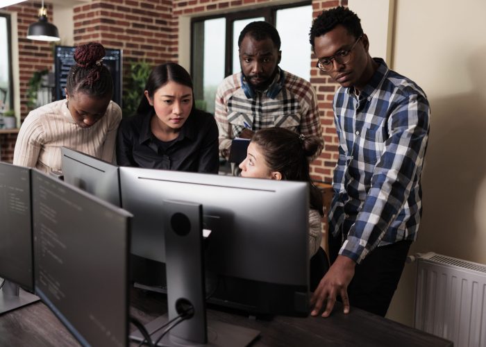 Multiethnic cyber security team developing software algorithm for information processing and network optimization. Informational agency multiracial tech engineers programming application while using computer.